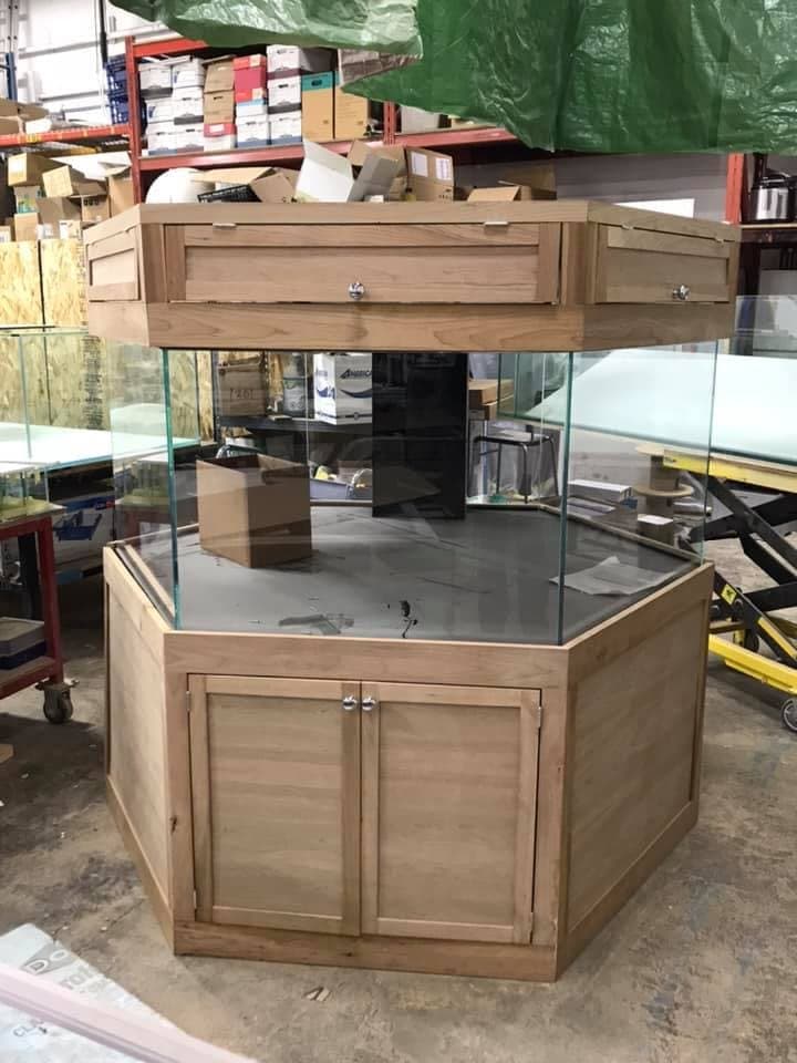 A custom hexagonal glass aquarium with matching wood cabinet assembled in the workshop