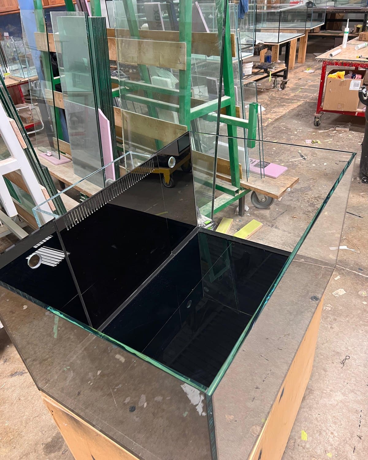 A braced glass aquarium with a black internal overflow during fabrication