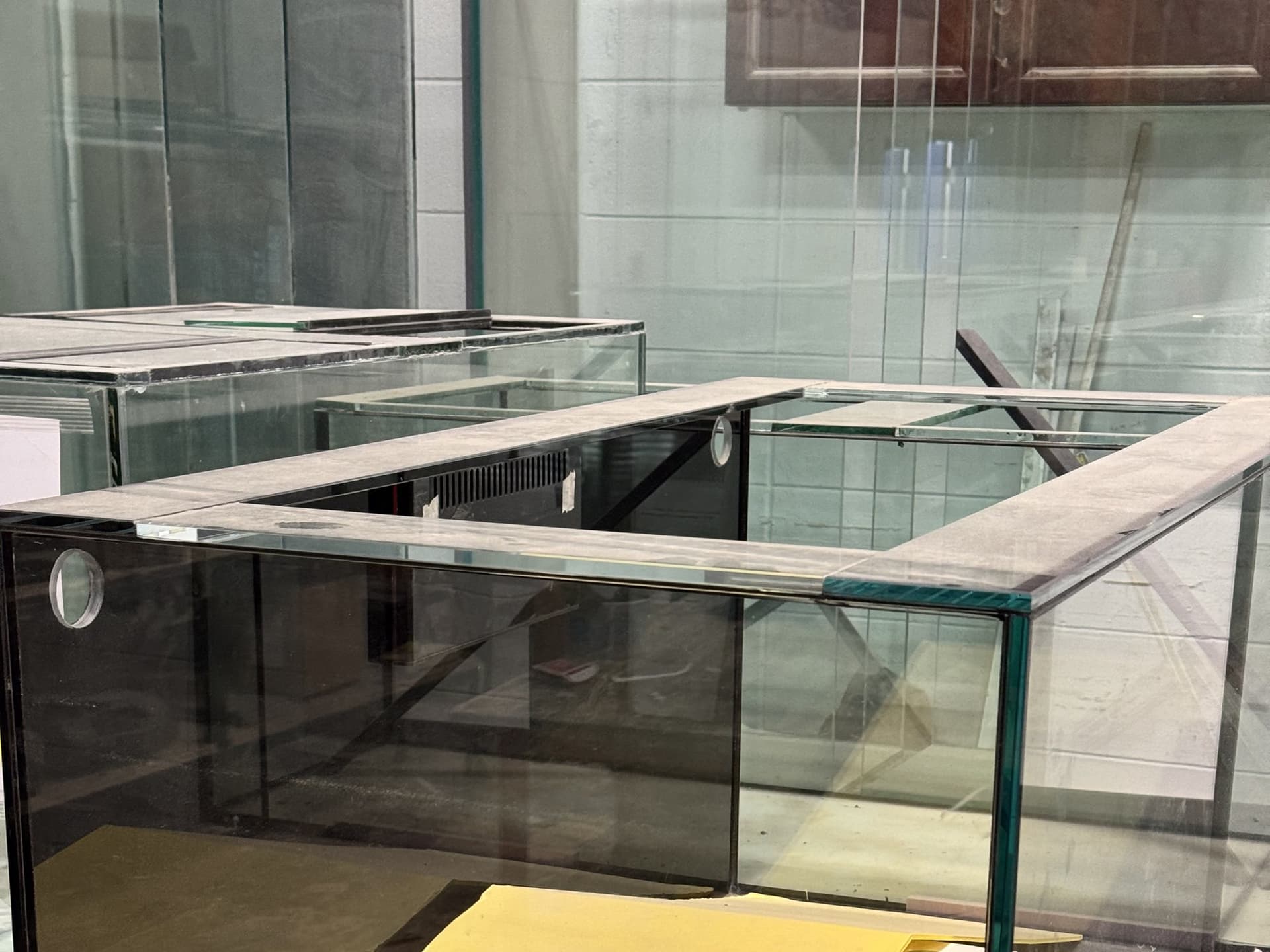 Multiple braced glass aquariums staged together in the workshop