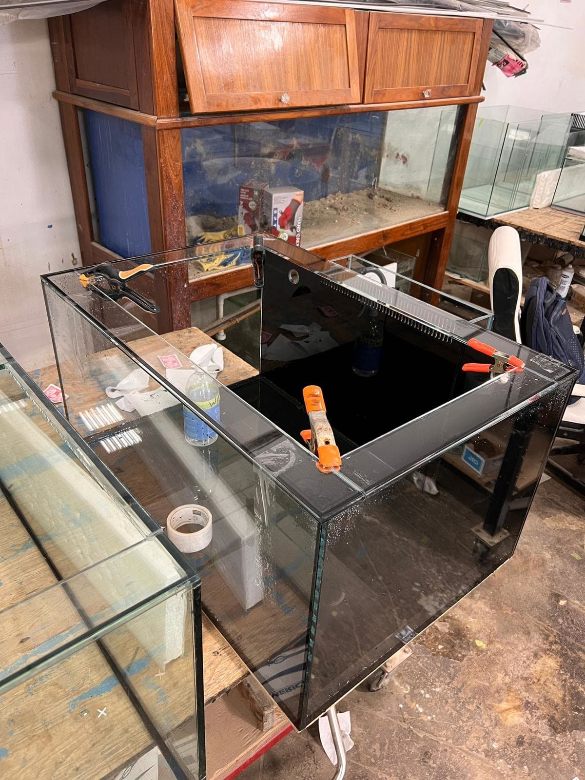 A black and clear glass sump clamped during assembly in the workshop